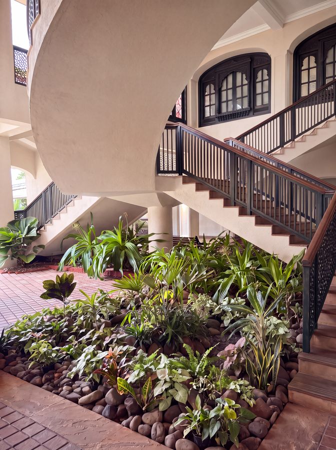 Stair-hall atrium — Layered foliage beds with pebble edging
